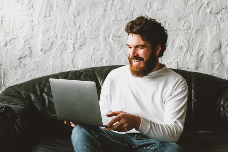Photo charming young man working at home in laptop