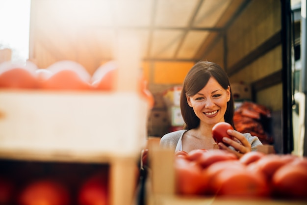 Charming young woman buying tomatoes.