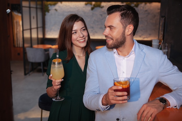 Foto giovane donna affascinante che flirta con il giovane bello al cocktail bar