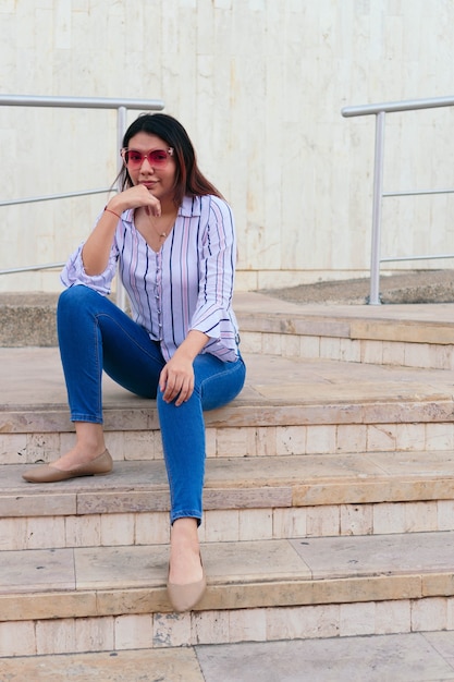 Charming young woman sitting on the city stairs