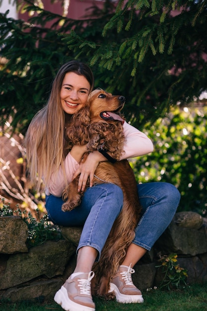 Charming young woman with beaming smile with her dog playing out