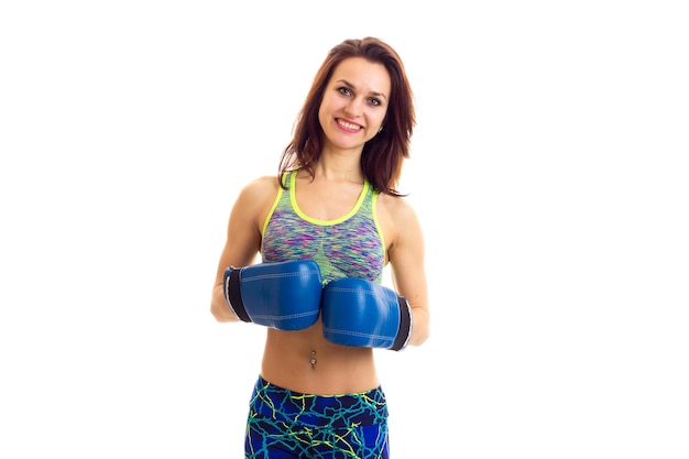 Charming young woman with brown long hair wearing in colored sports top with blue boxing gloves