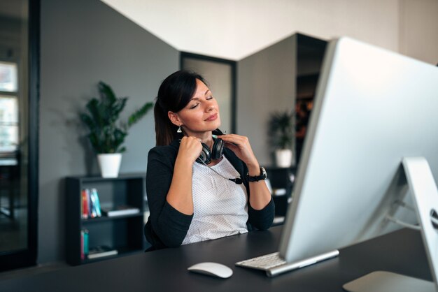 Charming young woman with closed eyes sitting at office desk.