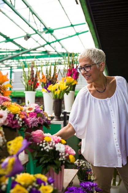 Charrming senior vrouw bloemen kopen op de markt