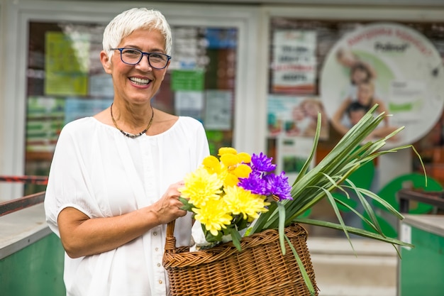 Charrming senior woman buying  flowers on  market