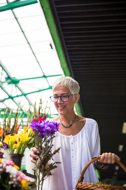 市場で花を買う魅力的な年配の女性