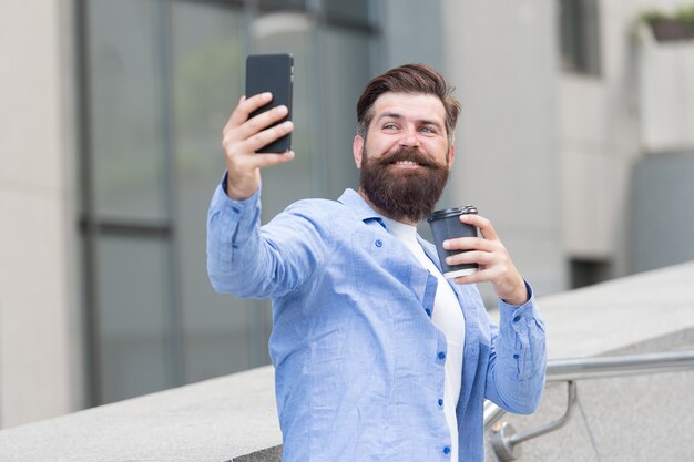 オンラインで友達とチャットしたり会ったりします。ひげを生やした男性が携帯電話を介してオンラインでチャットします。オンライン会議。モバイルデバイスでの音声またはビデオ会議。オンラインビデオ通話。スマートフォン通信。