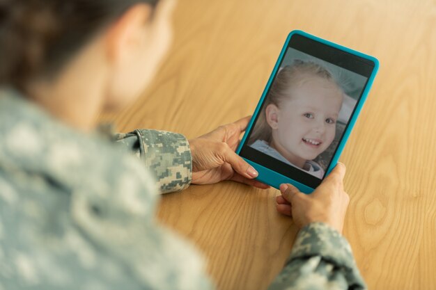 Chiacchierando con la figlia. donna matura che indossa l'uniforme militare in chat con la figlia utilizzando tablet