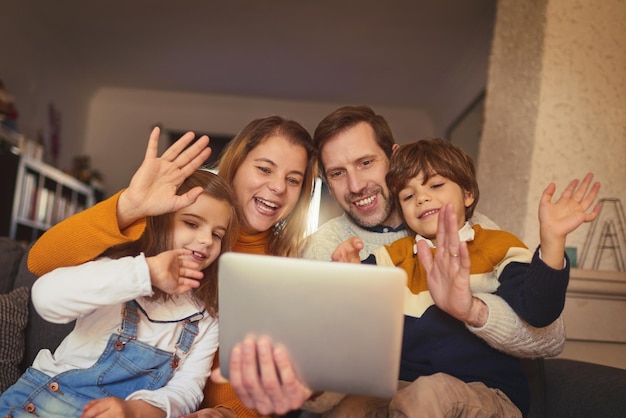 Chatting with family all across the globe Cropped shot of an affectionate young family of four video chatting using a digital tablet on the sofa at home