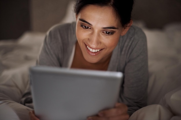 Chatting with him late into the night Cropped shot of an attractive young woman using her tablet in bed