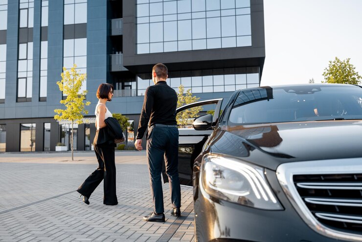 Foto chauffeur helpt een elegante zakenvrouw in de auto te stappen door de deur van een premium taxi te openen in de buurt van een kantoorgebouw of hotel concept van persoonlijke chauffeur of zakenreizen