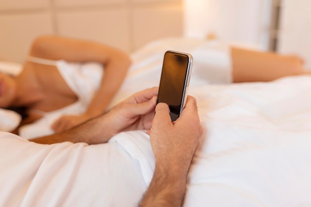Cheating unfaithful man lying with mistress in hotel bed Call from finace to mobile phone Cheater having affair with secret lover and relationship with another woman Infidelity and love triangle