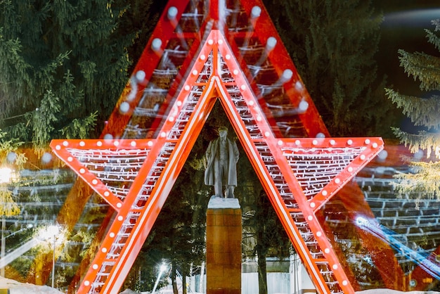 Cheboksary Russia November 08 2020 Monument to the historical figure Lenin in one of the city's parks against the backdrop of a light installation in the form of a star