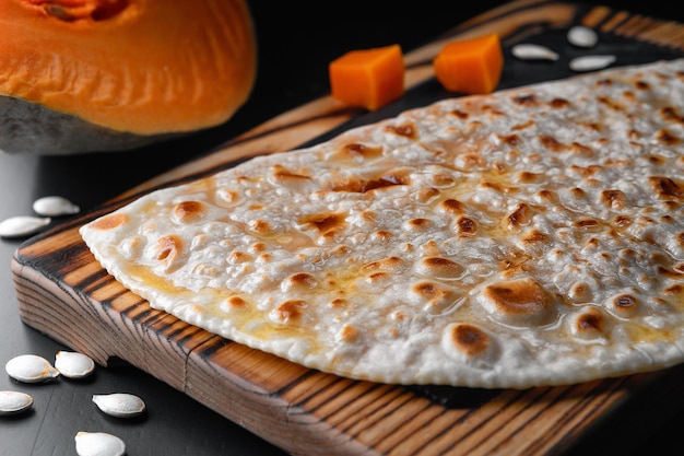 Cheburek pie with pumpkin on a wooden board