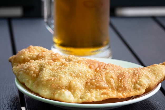 Foto chebureks con birra in stile rustico su uno sfondo di legno. torta salata di carne