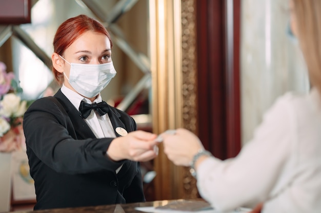사진 호텔 체크인. 바이러스에 대한 예방 조치로 의료 마스크를 착용 한 호텔의 카운터에서 접수. 호텔에서 체크인을 하 고 출장에 젊은 여자