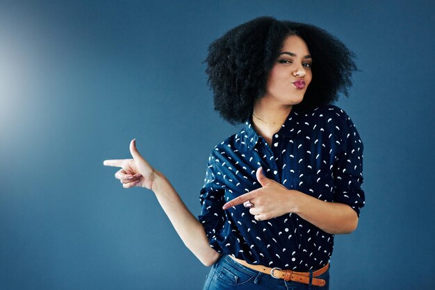 Check it studio shot of a young woman gesturing towards copy space against a blue background