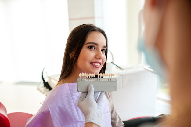 Check and select the color of the teeth for beautiful brunet girl.