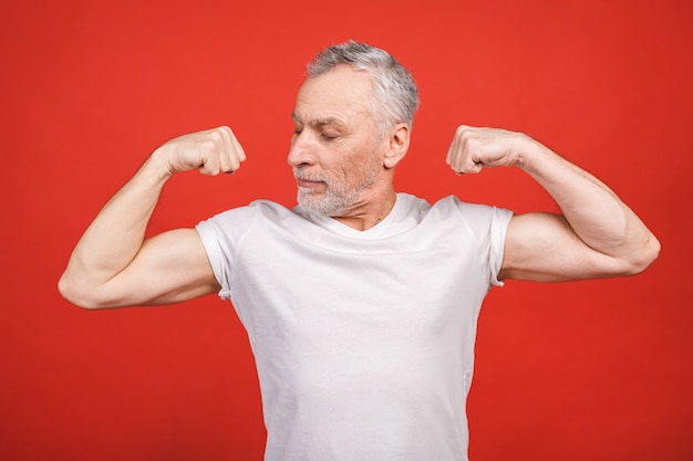 Check this out! Senior man showing muscle. Aged man flexing his arms isolated. Cheerful excited modern cool pensioner grandpa practising bodybuilding.