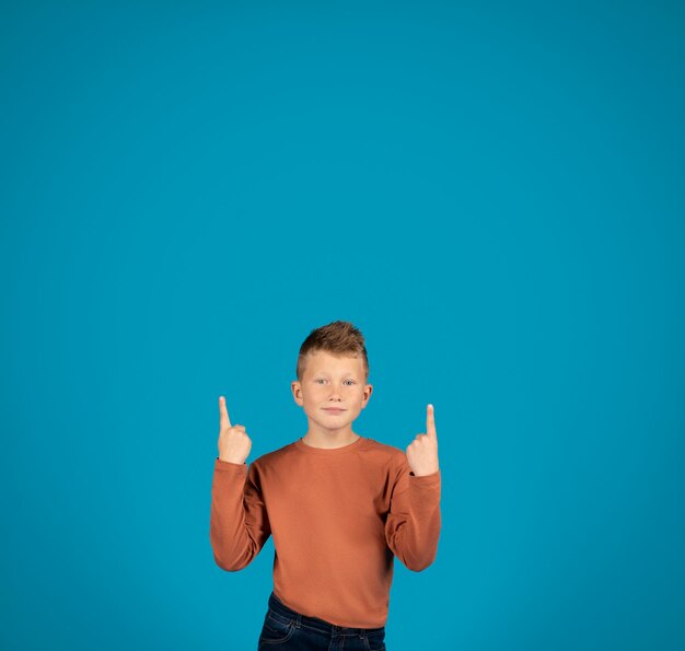 Check This Smiling preteen boy pointing up at copy space above head