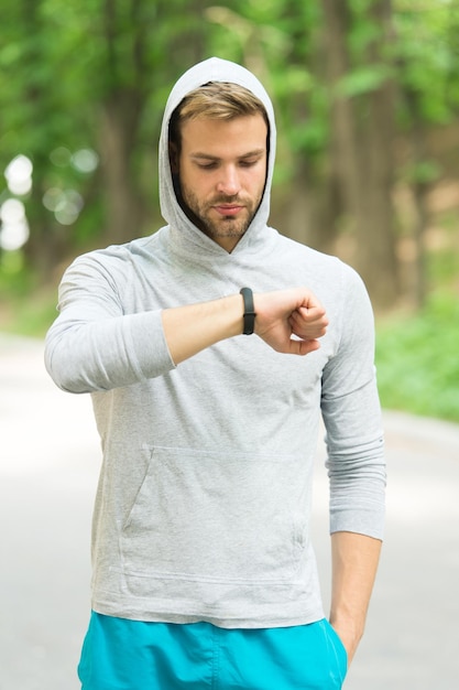 Check time his best score. Man athlete busy face check fitness tracker nature background. Athlete with bristle looks at fitness tracker or pedometer. Sportsman training with pedometer gadget.