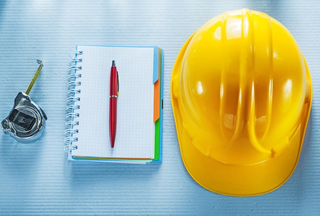 Checked notebook pen hard hat tape measure