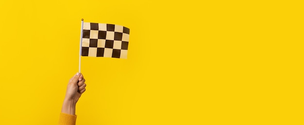 Checkered flag in hand over yellow background, panoramic image