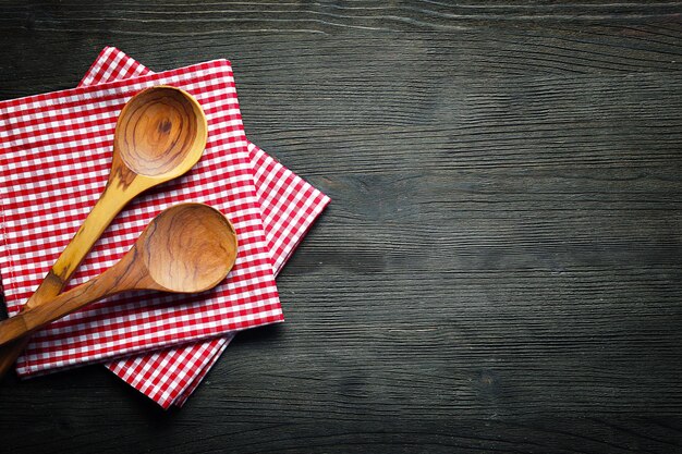 Checkered napkin and spoons on wooden background