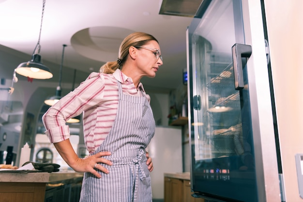 Photo checking availability. blonde-haired hard-working worker of bakery checking the availability of desserts