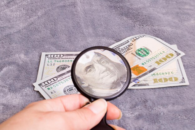 Checking dollar bill for authenticity with magnifying glass