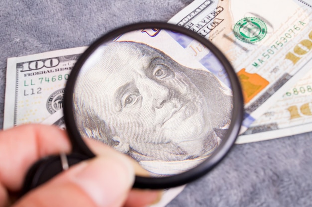 Checking dollar bill for authenticity with magnifying glass