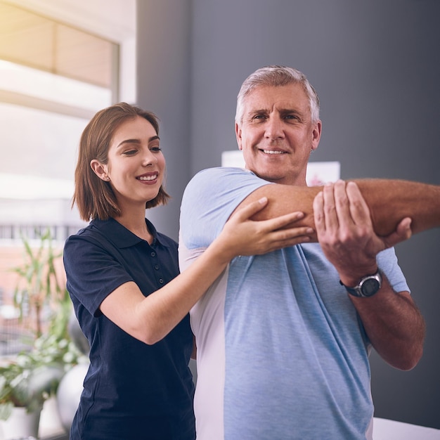 Photo checking on his mobility cropped shot of a young female physiotherapist treating a mature male patient