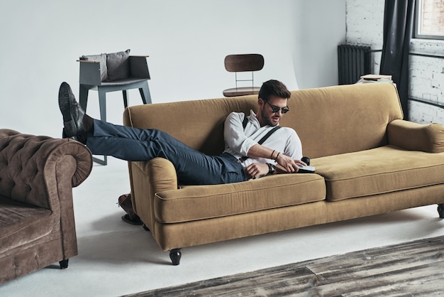 Photo checking out his camera. handsome young man touching his photo camera while lying on sofa