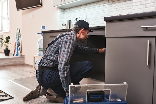 Checking problems young adult handyman repairing washbasin