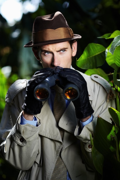 Checking up on you Private investigator using binoculars to spy on someone from the bushes