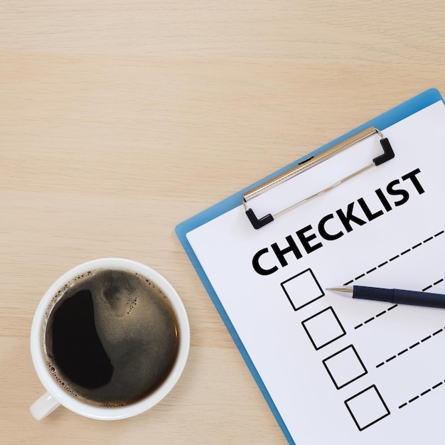Checklist box op klembord met pen en koffiekopje op houten tafel. check keuze antwoord test. checklist informatie schrijven.