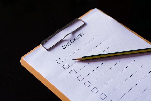 Photo checklist concept - checklist, paper and a pen with checklist word on wooden table