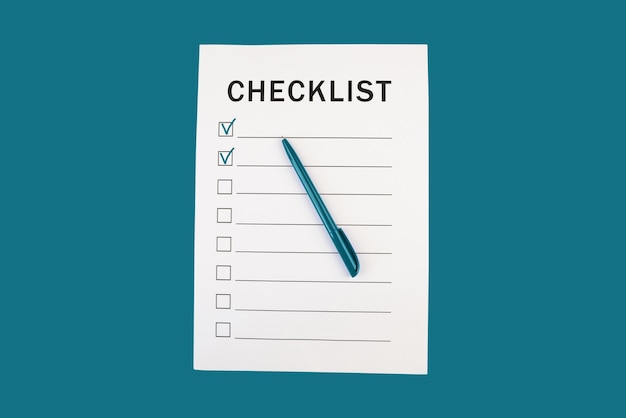 checklist and pen on blue background top view copy space
