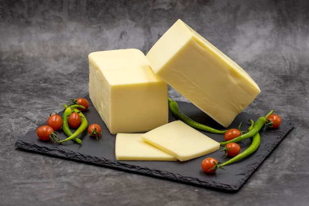 Cheddar cheese or kashkaval cheese on dark background Cheese slices on the serving board