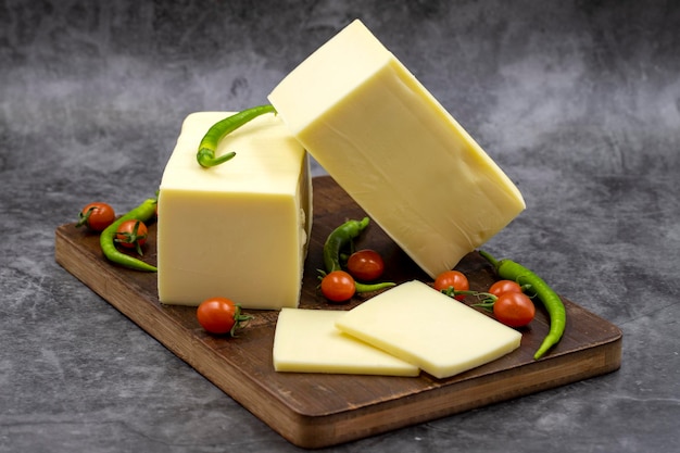 Cheddar cheese or kashkaval cheese on dark background Cheese slices on the serving board