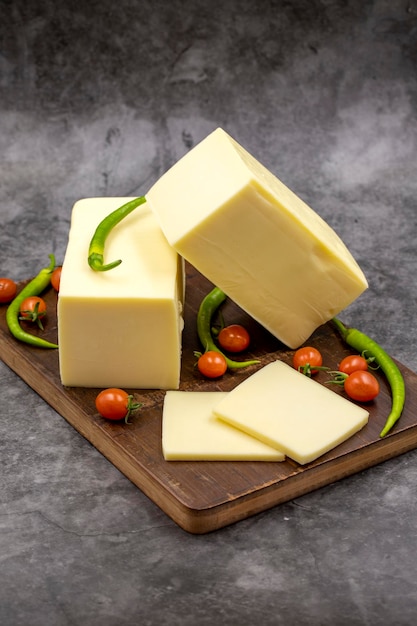 Cheddar cheese or kashkaval cheese on dark background Cheese slices on the serving board