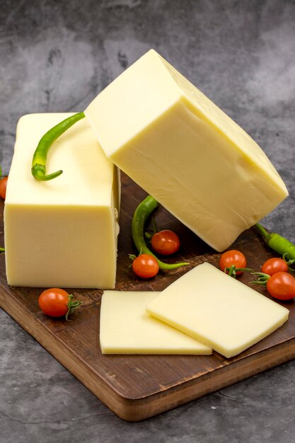 Cheddar cheese or kashkaval cheese on dark background Cheese slices on the serving board