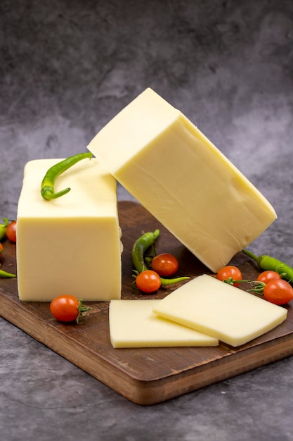 Cheddar cheese or kashkaval cheese on dark background Cheese slices on the serving board