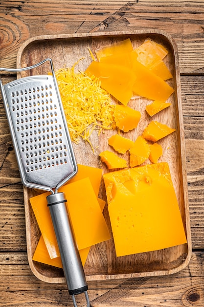 Cheddar Kaas Geraspt en in blokjes gesneden in een houten bakje. houten achtergrond. Bovenaanzicht.