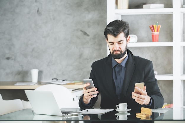 Cheeky businessman using two smartphones