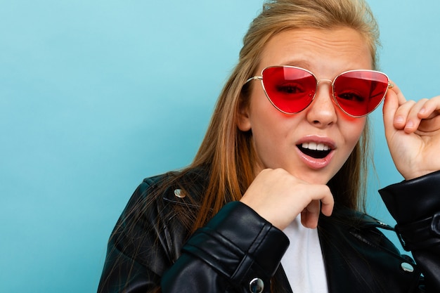 Cheeky european girl in glasses on light blue