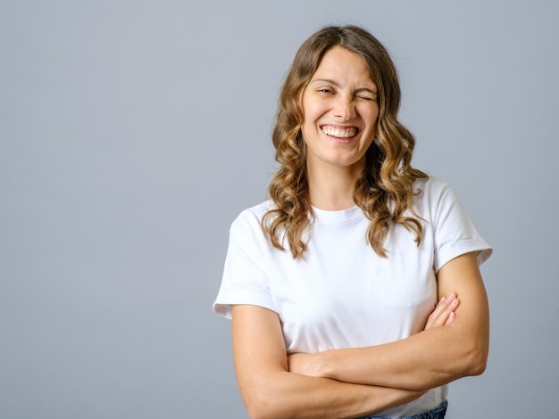 Cheeky woman smiling and winking at camera with confidence cross arms on chest