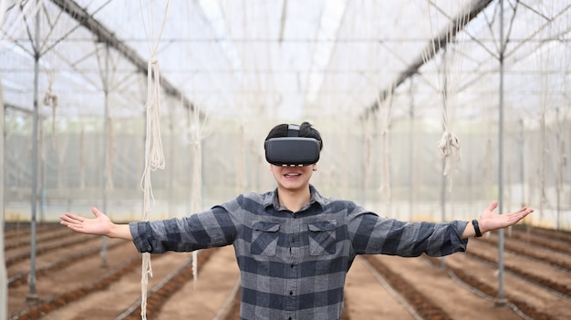 Развеселить умного фермера в очках визуальной реальности, стоя в теплице.