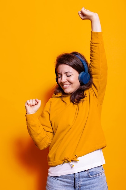 Cheerful adult enjoying song on headphones and dancing to have fun. woman feeling happy and listening to music on headset while doing dance moves smiling. positive active person