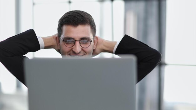 Cheerful adult european guy have break from work at laptop with hands behind his head